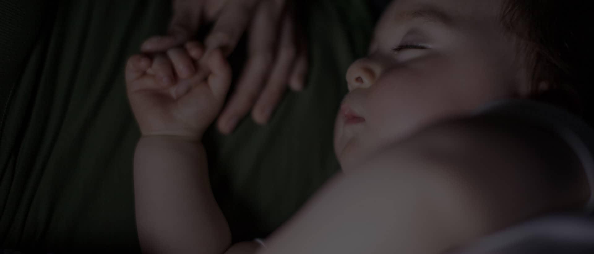 sleeping baby holding mother's arm